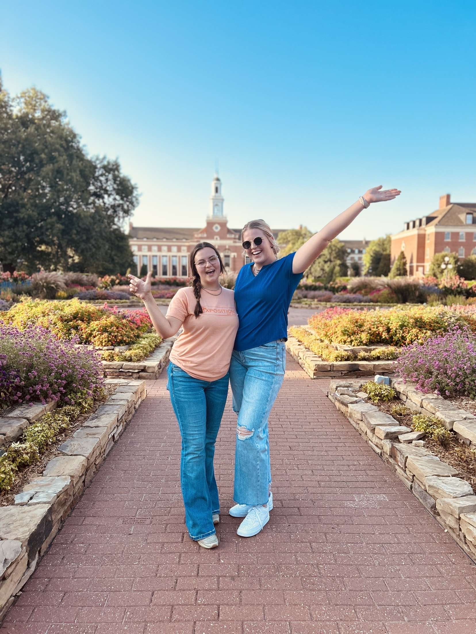 Two female students posing in front of a large green space