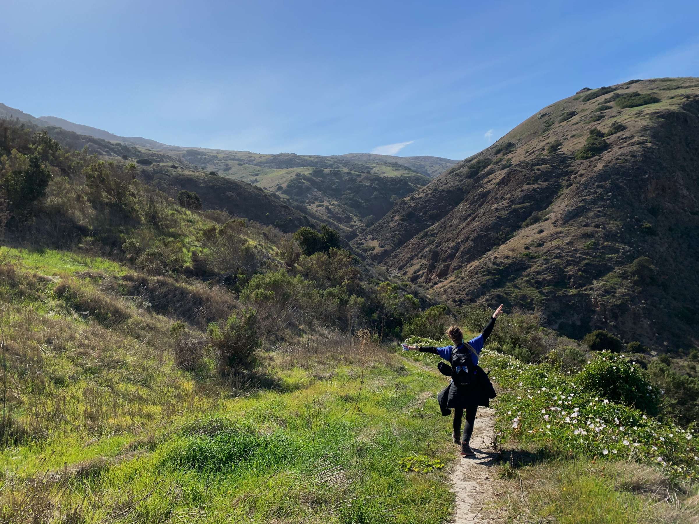 Image shows a student posing along a lush hiking trail