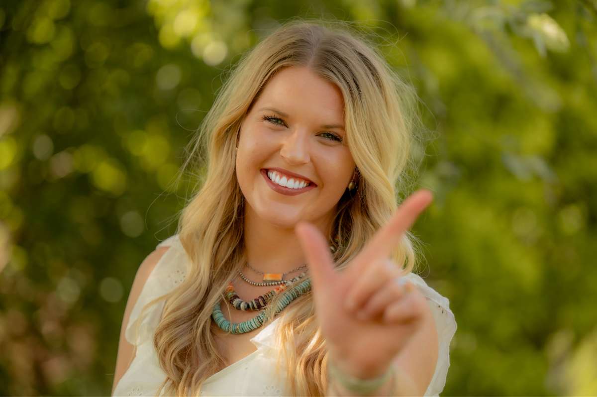 A female student poses with the Oklahoma State University "go pokes" hand signal 